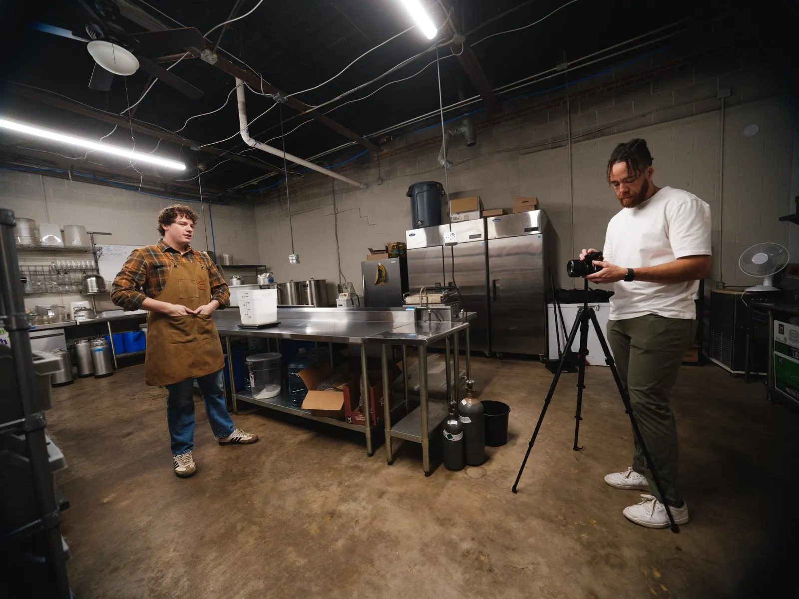 Tyler Thompson setting up a camera on a tripod in a commercial kitchen