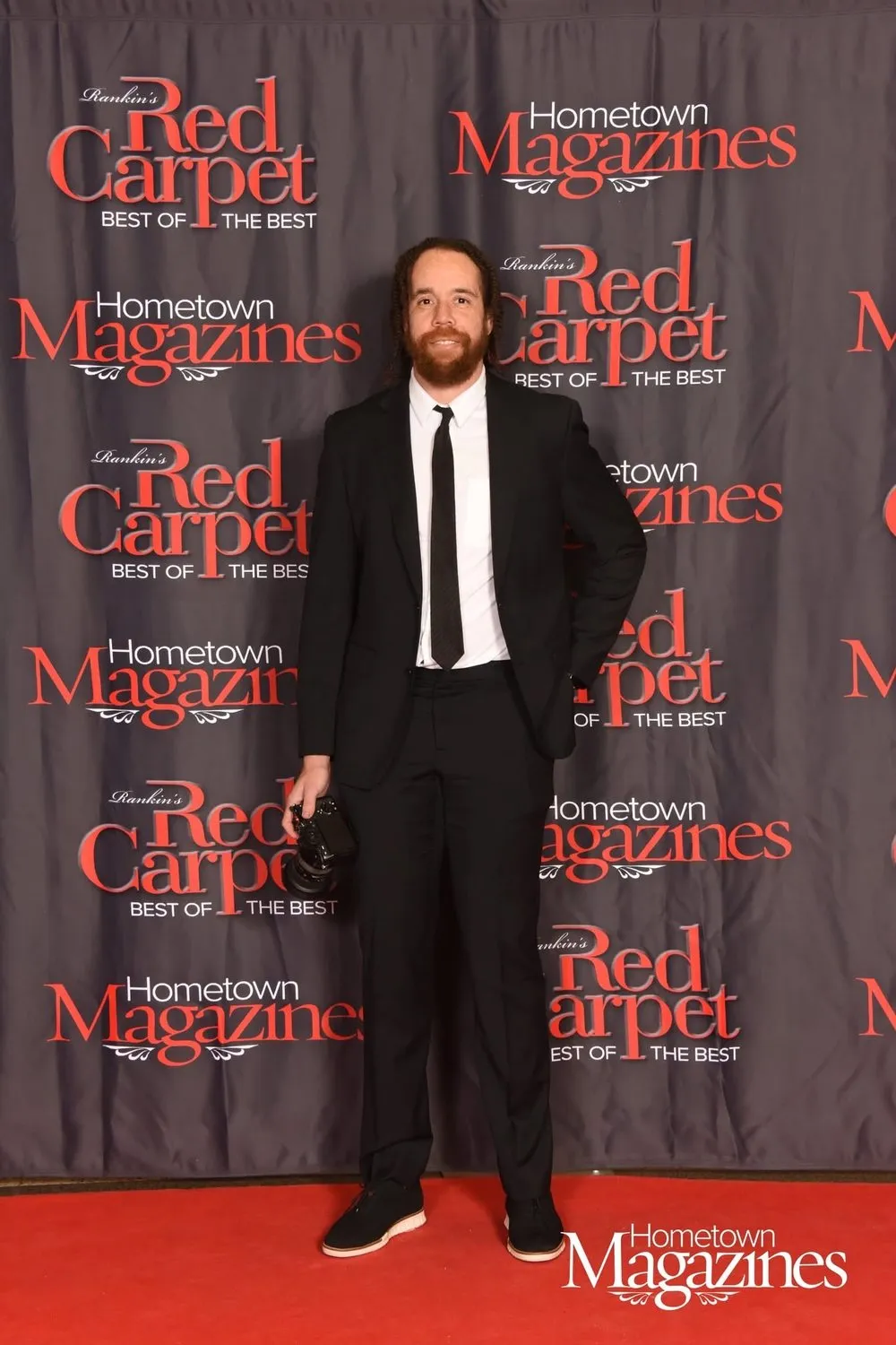 Tyler Thompson in a black suit on the red carpet, in front of a Rankin's Red Carpet Best of the Best backdrop from Hometown Magazines
