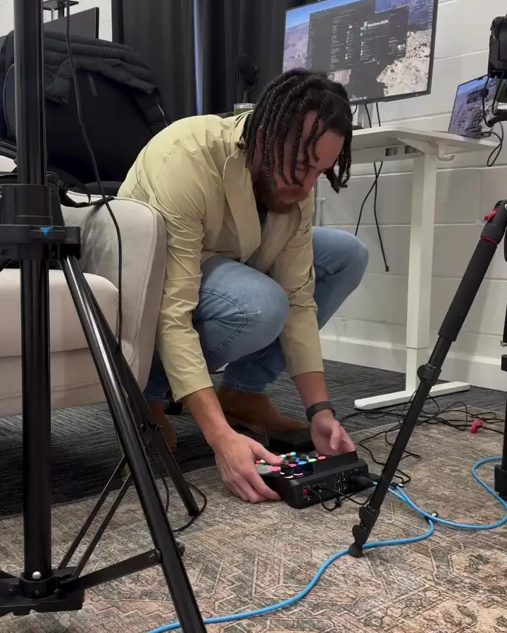 Tyler Thompson crouched beside a camera tripod, setting up gear before a shoot